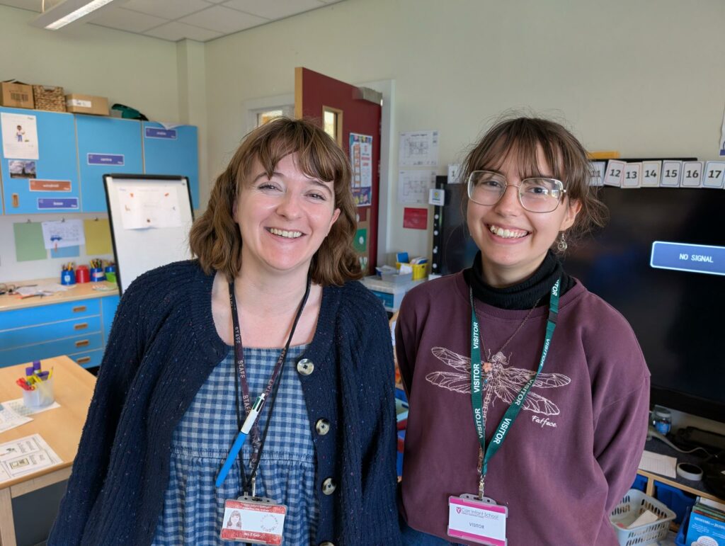 Teacher and Climate Ambassador standing in school classroom smiling as they meet