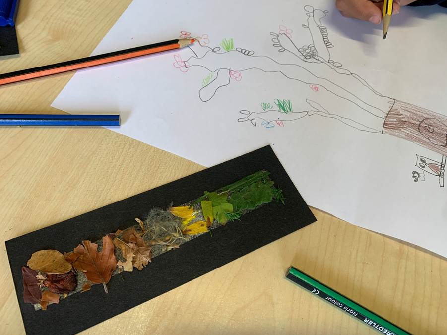 A child creating a nature-inspired artwork, drawing a tree on paper with coloured pencils, alongside a strip decorated with leaves and moss.