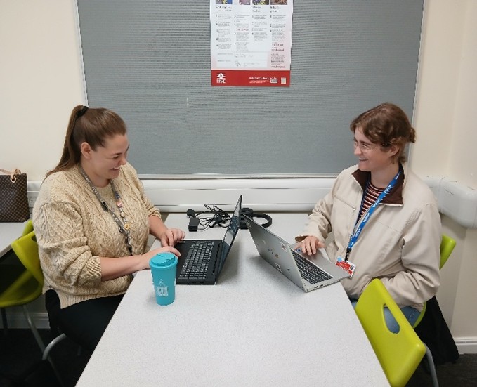 Alana and Natasha sat oposite each other working at a desk