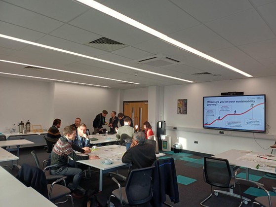 Groups of people sat at desks sharing their ideas for sustaiability