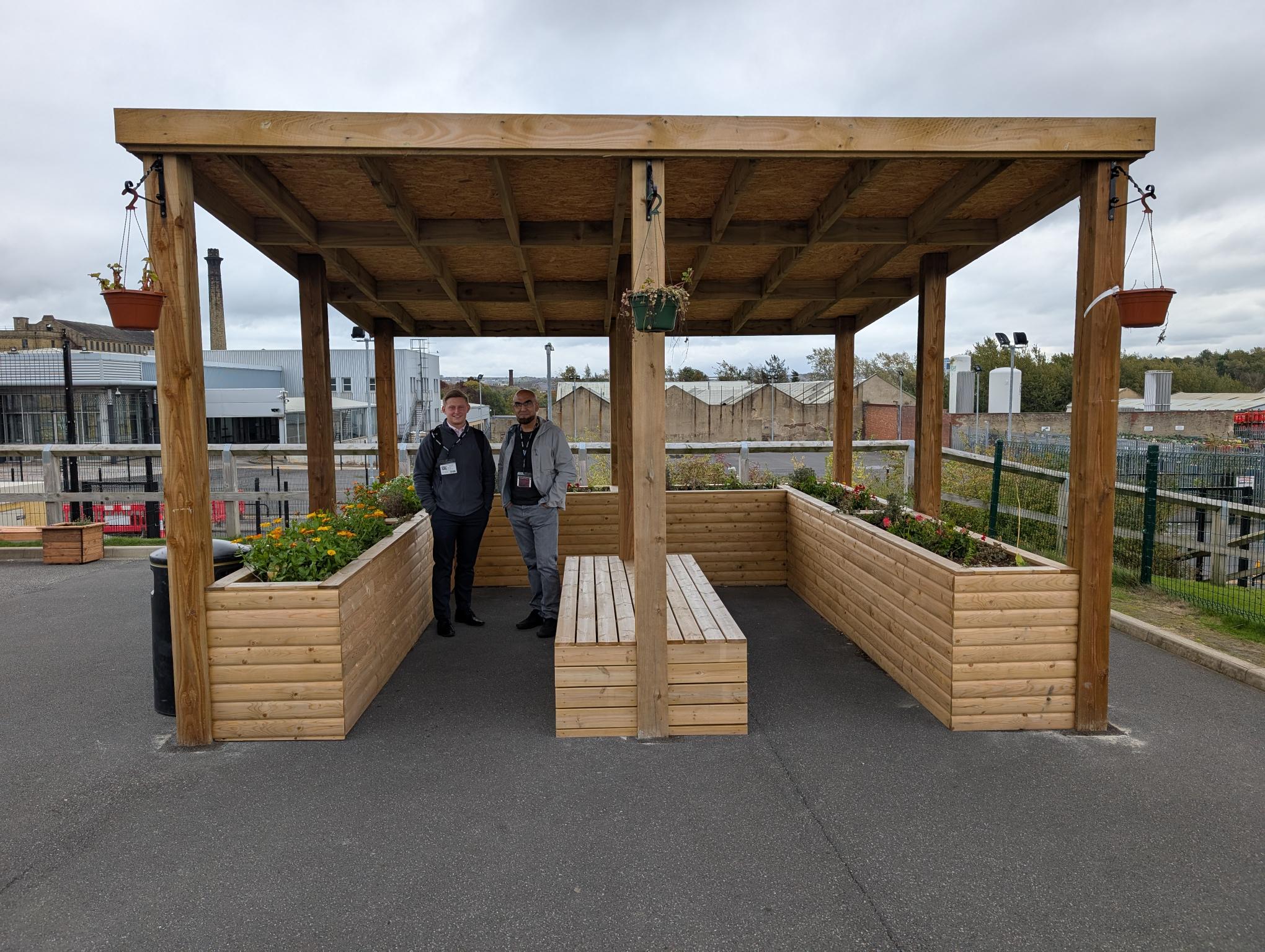Adults smiling and posing in a school's outdoor learning space, surrounded by raised planters.