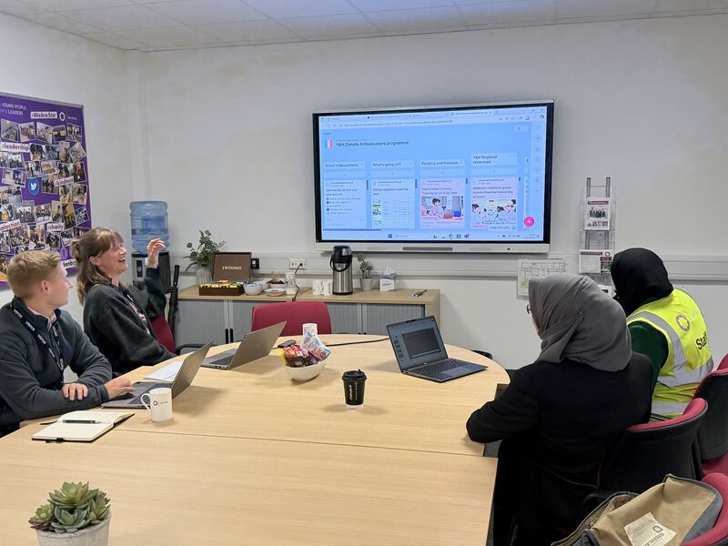 Climate Ambassadors and school leaders sit around a table, discussing climate action planning